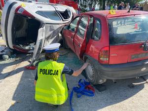 policjantka kucająca przy samochodach biorących udział w wypadku
