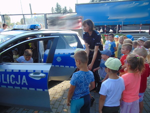 policjantka pomagająca wsiadać przedszkolakom do radiowozu