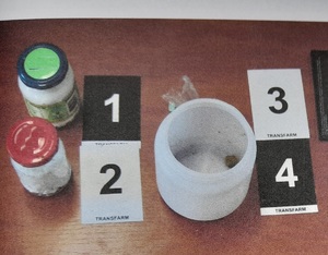 słoiczki oraz pojemnik z narkotykami obok znaczniki z numerami