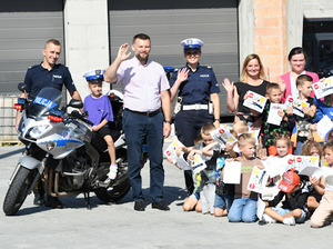 Umundurowani policjanci oraz policyjny motocykl,  Wójt Gminy Lipnica Murowana oraz dzieci biorące udział w prelekcji