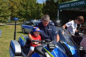 dziecko siedzi na policyjnym motocyklu obok stoi policjant