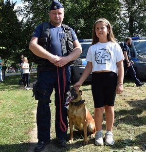 dziewczynka pozuje do zdjęcia z policyjnym przewodnikiem i psem służbowym