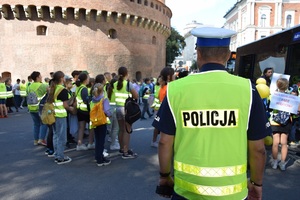 policjant koordynuje wsiadanie do autobusów  przez uczestników marszu