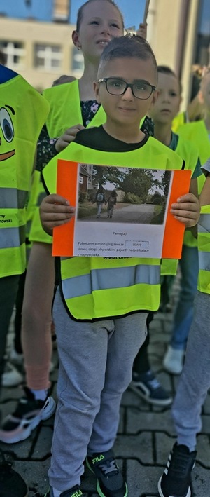chłopiec w kamizelce odblaskowej trzymający plakat
