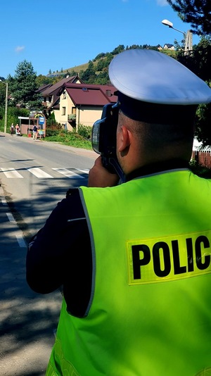 policjant mierzy prędkośćpojazdów  ręcznym miernikiem prędkości