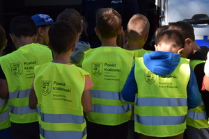 dzieci stojące tyłem w kamizelkach odblaskowych z napisem bezpieczny powiat krakowski