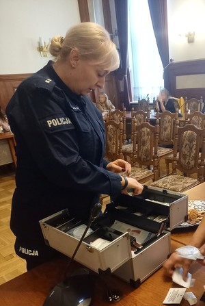 policjantka otwierajaca walizkę edukacyjną z imitacją dopalaczy