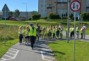 policjantka prowadzi dzieci po miasteczku ruchu drogowego