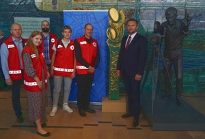 Zastępca Komendanta wraz z sołtysem oraz grupą PCK pozuje do zdjęcia z duża statuetka samarytanina