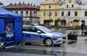 Baner Komendy Powiatowej Policji w Bochni oraz policyjny radiowóz na tle bocheńskiego rynku
