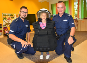 Uczennica przedszkola w umundurowaniu policyjnym obok dwóch policjantów