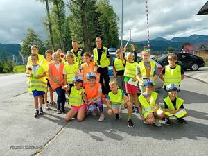 dzieci w kamizelkach odblaskowych i policjant ruchu drogowego