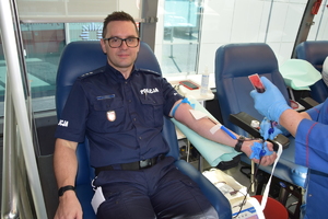 umundurowany policjant podczas oddawania krwi siedzący w krwiobusie