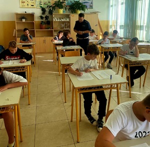 policjant w klasie pilnuje uczniów którzy rozwiązuja test