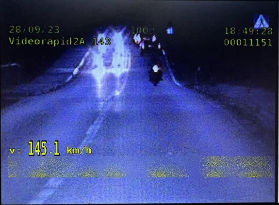 Zdjęcie motocyklisty jadącego drogą, po lewej stronie zarejestrowana jego prędkość 145,1 kmh. W górnej części zdjęcia data i godzina wykroczenia.