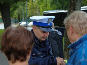 Policjant wręcza kobietom elementy odblaskowe