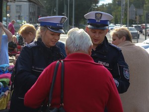 Policjantka i policjant wręczają kobiecie element odblaskowy