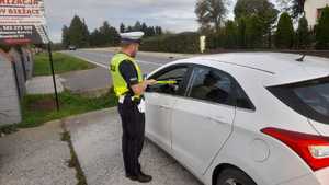 Policjant ruchu drogowego wręcza opaskę odblaskową kierowcy podczas kontroli drogowej