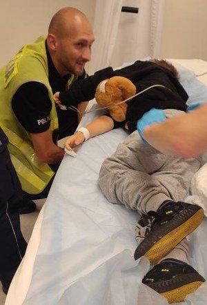 policjant przy szpitalnym łóżku chłopczyka