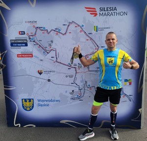 Jakub Ciągło ultramaratończykiem policjant w stroju sportowym na tle mapy maratonu