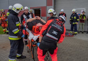 strażacy przekazują rannego strażakom ze zintegrowanej służby ratowniczej