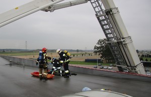 strażacy na dachu udzielają pomocy rannemu pracownikowi