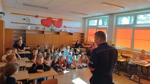 policjant w sali lekcyjnej tłumaczy dzieciom zasady bezpieczeństwa