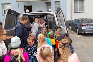 Zwiedzanie komendy Pierwszaki z Brzezinki zastępca naczelnika prezentuje dzieciom radiowóz dzieci przy radiowozie