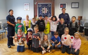 Zwiedzanie komendy Pierwszaki z Brzezinki policjantki na wspólnym zdjęciu z uczniami na tle sztandaru KPP Oświęcim