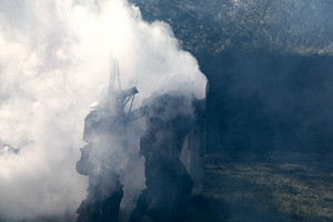 policjant z tarczą zostawia za sobą łunę dymu