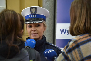 Policjantka ruchu drogowego udzielająca wywiadu na stacji diagnostycznej. Widoczne mikrofony stacji radiowych Meloradio i Radio Kraków