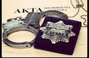 kajdanki i gwiazda policyjna na obwolucie akt