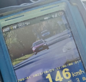 zdjęcie monitora miernika prędkości z zarejestrowanym czerwonym  samochodem jadacym z prędkością 146 kilometrów na godzinę