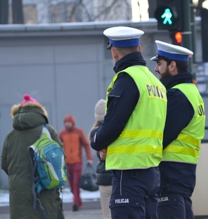 Policjanci ruchu drogowego nadzorują ruch pieszych w rejonie  przejścia z sygnalizacją świetlną