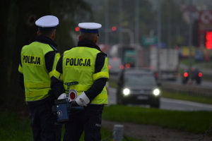 Dwóch policjantów ruchu drogowego nadzoruje ruch na drodze. Jeden z nich...