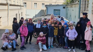 dzieci pozują z policjantką do wspólnego zdjęcia na dziedzińcu komisariatu