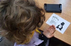 dziecko odbija odcisk swojej dłoni na karteczce z policyjną maskotką