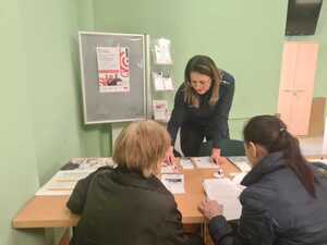 policjantka rozmawia z osobami oczekującymi na załatwienie swoich spraw