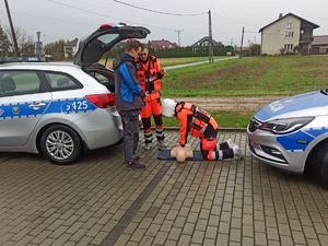 Akcja Żyj i ratuj życie w Jawiszowicach uczennica prezentuje resuscytację obok nauczyciel i kierowca