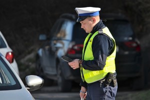 Policjant ruchu drogowego wykonujący przejeżdżającym kierującym szybkie badanie trzeźwości