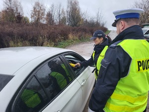 policjantka badająca trzeźwość kierowcy, za nią stoi drugi policjant