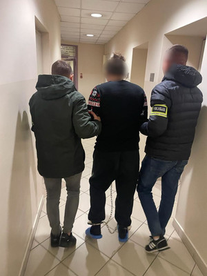 dwóch nieumundurowanych policjantów prowadzi przez korytarz krakowskiej komendy zatrzymanego mężczyznę