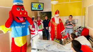 policjantka z świętym mikołajem i aniołkami oraz maskotką polickiem stoją w pokoju z dziećmi leżacymi na łóżkach w szpitalu