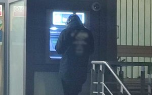 zatrzymany mężczyzna stojący przy bankomacie.jpg