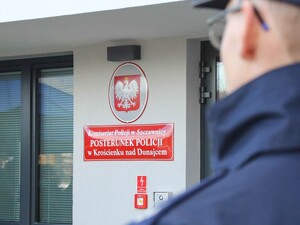 Czerwona tablica z napisem "Komisariat Policji w Szczawnicy POSTERUNEK POLICJI w Krościenku nad Dunajcem" nad nią Herb Rzeczypospolitej Polskiej