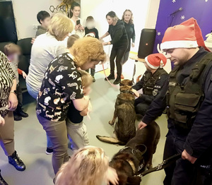 policjanci, psy służbowe, dzieci z ośrodka oraz wychowawczynie w jednej sali podczas wspólnego spotkania