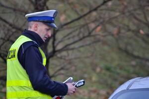Policjant ruchu drogowego podczas kontroli drogowej, trzymający w ręku urządzenie elektroniczne do badania trzeźwości