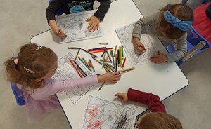 dzieci siedzące przy stoliku kolorujące obrazki