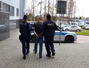 umundurowani policjanci prowadzą mężczyznę w strone radiowozu