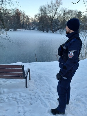 policjant sprawdzający zamarznięty zbiornik wodny na terenie miasta